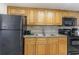 Compact kitchen area with wood cabinets, black appliances, and light-colored countertops at 3000 N Ocean Blvd. # 1020, Myrtle Beach, SC 29577