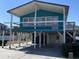 A stilted teal home showcasing the structure and access stairs, needing some love at 317 29Th Ave. N, North Myrtle Beach, SC 29582