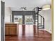 Open living room boasts wood floors, a spiral staircase, and balcony views of the outdoor pool at 3700 Golf Colony Lane # 5J, Little River, SC 29566