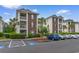 Exterior shot of condo community with brick and siding, lush landscaping, and assigned parking at 480 River Oaks Dr. # 63-O, Myrtle Beach, SC 29579