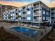 Coastal condo building at sunset, featuring a swimming pool and multiple levels with white balconies at 5600 Ocean Blvd. N # A11, North Myrtle Beach, SC 29582