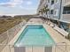 Exterior view of a community pool, with lounge chairs and the ocean visible in the background at 5600 Ocean Blvd. N # A11, North Myrtle Beach, SC 29582