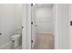 Bright bathroom featuring a toilet, beige carpeted walk-in closet with wire shelving, and neutral wall color at 7005 Grant St., Little River, SC 29566