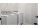 This bright laundry room contains a white washer and dryer with a wire shelf for storage at 7005 Grant St., Little River, SC 29566
