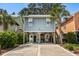 Coastal beach house featuring blue siding, white trim, raised design with covered parking, and lush landscaping at 77 Weatherboard Ct., Pawleys Island, SC 29585