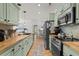 Galley kitchen with stainless steel appliances, wood countertops, and sage green cabinetry at 77 Weatherboard Ct., Pawleys Island, SC 29585