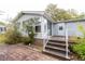 A charming exterior with brick steps, white railings, gray siding, a sunroom and mature landscaping at 835 South Marlin Circle, Murrells Inlet, SC 29576