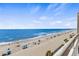 Picturesque beach view from a condo balcony showcasing the ocean, shoreline and people enjoying the sand and surf at 1012 N Waccamaw Dr. # 507, Murrells Inlet, SC 29576
