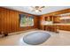 Living room features knotty pine walls, a window, ceiling fan, and blue woven rug at 2192 Highway 308, Galivants Ferry, SC 29544