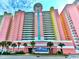 A large condo building with colorful exterior near a green landscape and clear skies at 2701 S Ocean Blvd. # 1507, North Myrtle Beach, SC 29582