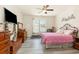 Bright bedroom with hardwood floors, ceiling fan, large windows, and a cozy pink-covered bed at 524 Cottage Oaks Circle, Myrtle Beach, SC 29579
