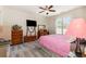 Bright bedroom with hardwood floors, ceiling fan, large windows, and a cozy pink-covered bed at 524 Cottage Oaks Circle, Myrtle Beach, SC 29579