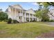 A two-story, light yellow apartment building with white columns and staircases and a grassy lawn at 5876 Longwood Dr. # 201, Murrells Inlet, SC 29576