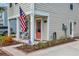 Inviting front porch with rocking chairs, complemented by attractive landscaping and charming coral front door at 9012 Mabel Ct., Longs, SC 29568