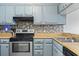A well-lit kitchen features light blue cabinetry, a stainless steel range, and a mosaic tile backsplash at 9501 Shore Dr. # B-316, Myrtle Beach, SC 29572