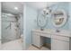 Bathroom with double sinks, tiled floor, shower, bright lighting, and framed round mirrors at 9820 Queensway Blvd. # 105, Myrtle Beach, SC 29572
