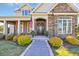 Inviting front entrance featuring stone accents, covered porch, and manicured landscaping at 107 Long Bay Golf Pl., Longs, SC 29568
