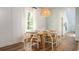 Bright dining room with wood floors, decorative light fixture and large window at 1166 Silver Perch Place, Sunset Beach, NC 28468