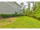 The home's grassy backyard features green siding on the home, along with mature trees and plantings at 128 Puffin Dr. # 1-E, Pawleys Island, SC 29585