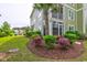 A lush lawn and landscaping surrounds a building with green siding, an enclosed porch, and a palm tree at 128 Puffin Dr. # 1-E, Pawleys Island, SC 29585