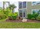 A lush lawn and landscaping surrounds a building with green siding, an enclosed porch, and a palm tree at 128 Puffin Dr. # 1-E, Pawleys Island, SC 29585