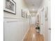 Long hallway with wainscoting and decorated with decorative photos and wooden floors at 179 S Reindeer Rd., Surfside Beach, SC 29575