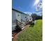 Exterior shows mobile home’s door and wooden stairs, surrounded by a green yard and trees under a clear blue sky at 3802 Stern Dr., Conway, SC 29526