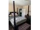 Bedroom showcasing a four-poster bed with decorative pillows, a patterned ottoman, and dark wood floors at 402 Gibson St., Marion, SC 29571