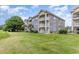 View of multi-story condo building with stone accents, balconies and mature landscaping at 4709 Wild Iris Dr. # 101, Myrtle Beach, SC 29577