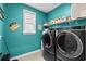 Modern laundry room with blue walls, front load washer and dryer and wire rack at 143 Starlit Way, Myrtle Beach, SC 29579