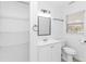 A bright bathroom features a sink with cabinet, a mirror, open shelving, a toilet, and a window at 1931 Jasper St., Georgetown, SC 29440