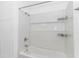 White tiled bathtub and shower combo featuring open shelving and silver hardware at 1931 Jasper St., Georgetown, SC 29440