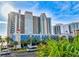 Stunning exterior view of a high-rise condo with a clock tower, blue awnings, and palm trees set against a blue sky at 2401 S Ocean Blvd. S # 267, Myrtle Beach, SC 29577