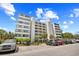 Low-angle view of a multistory condo building with ample parking, landscaping, and beautiful blue sky at 311 71St Ave. N # 3-D, Myrtle Beach, SC 29572