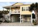 Elevated beach house featuring a covered porch, exterior staircase, and covered parking area at 412 29Th Ave. N, North Myrtle Beach, SC 29582