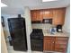 Compact kitchen featuring a black refrigerator, oven, microwave, and wood cabinets, offering essential amenities at 5300 N Ocean Blvd. # 310, Myrtle Beach, SC 29577