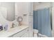Bright bathroom featuring a round mirror, vanity, and a shower with a blue curtain at 6001-1872 S Kings Hwy., Myrtle Beach, SC 29575