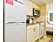 Compact kitchen with white cabinets, essential appliances, and adjacent bedroom for easy access at 9550 Shore Dr. # 531, Myrtle Beach, SC 29572