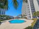 Beautiful blue pool surrounded by a high-rise building and lush green palm trees on a sunny day at 9820 Queensway Blvd. # 704, Myrtle Beach, SC 29572