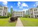 Exterior view of a three-story condo building with a sidewalk surrounded by a luscious green lawn at 1204 River Oak Dr. # 25-A, Myrtle Beach, SC 29579