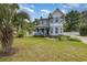 Charming light blue two-story home with a covered front porch and lush green lawn and mature landscaping at 221 Lander Dr., Conway, SC 29526