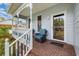 Cozy front porch with wicker chairs, white railings, brick floor, and view of the front yard at 221 Lander Dr., Conway, SC 29526