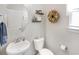 Charming powder room with a pedestal sink, round mirror, decorative shelves, and natural light at 3024 Calusa Dr., Little River, SC 29566