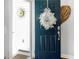 A view of the front door adorned with a white floral wreath with welcome sign at 3024 Calusa Dr., Little River, SC 29566