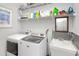 Functional laundry room with modern washer and dryer, utility sink, and storage shelving at 3024 Calusa Dr., Little River, SC 29566