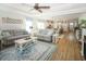 Open-concept living room with hardwood floors, ceiling fan, with two couches and a view into the kitchen and dining area at 3024 Calusa Dr., Little River, SC 29566