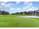 Scenic golf course with a pond, manicured green, and a flag on a sunny day at 404 75Th Ave N # G, Myrtle Beach, SC 29572
