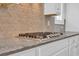 Modern kitchen features a stainless steel stovetop and stylish herringbone tile backsplash at 537 Indigo Bay Circle, Myrtle Beach, SC 29579