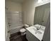 Well-lit bathroom with a shower-tub combo, white fixtures, and wood-look vinyl flooring at 624 Muster Field Ct., Conway, SC 29526