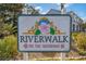 Community sign for 'Riverwalk on the Waterway' featuring a decorative flower at 679 Riverwalk Dr. # 202, Myrtle Beach, SC 29579